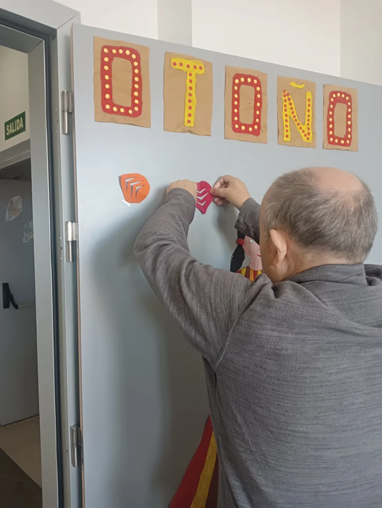 Talleres Campolar Ilusiones - residente decorando puerta con dibujos de otoño